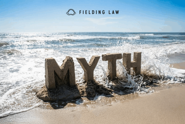 the word Myth made into a sandcastle wiped out by a wave at the beach