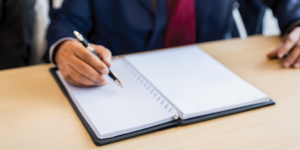 Attorney sitting at desk writing notes about a case during a consultation