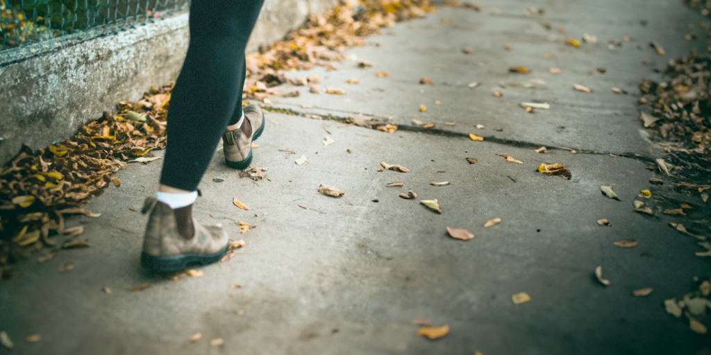 Woman walking on leaf covered sidewalk