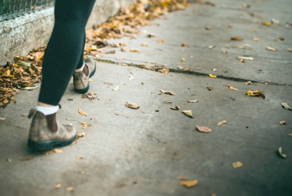 Woman walking on leaf covered sidewalk