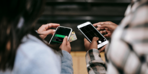 Two people taking photos with their phones of insurance cards and drivers licenses