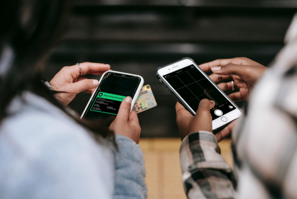 Two people taking photos with their phones of insurance cards and drivers licenses