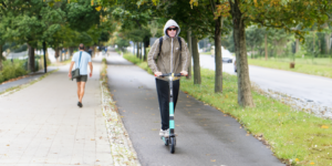 Man walking by another man on an e-scooter