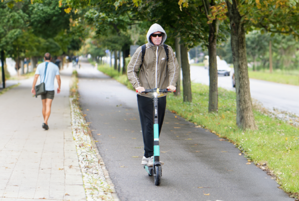 Man walking by another man on an e-scooter