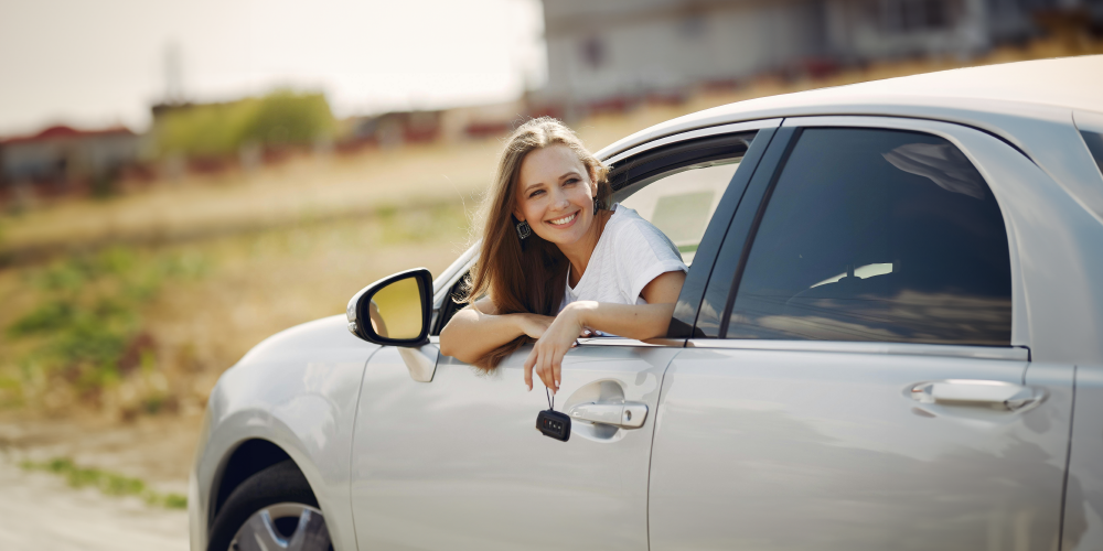 Female teenager sitting in a car holding keys. Teen Driver Safety Week