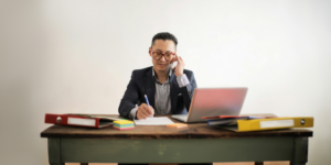 Man sitting at a desk while talking on the phone.