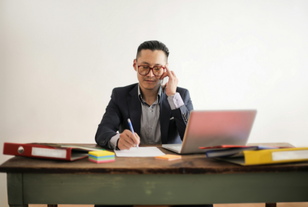 Man sitting at a desk while talking on the phone.