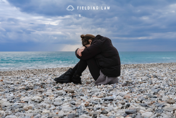 person sitting on a California beach head burried in legs. Suffering from PTSD