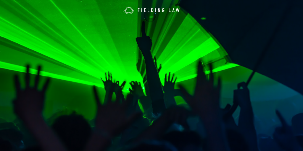 Green burst of light at a rave with people's hands in the air