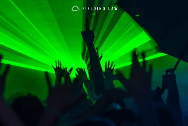 Green burst of light at a rave with people's hands in the air