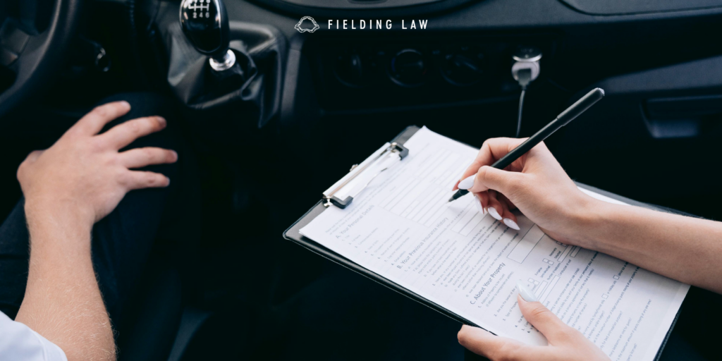 person holding a clipboard in car looking over vehicle insurance requirements