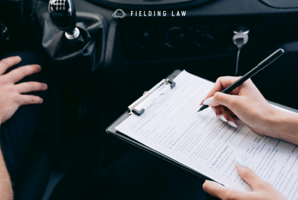 person holding a clipboard in car looking over vehicle insurance requirements