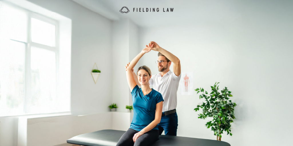 Woman sitting on a table stretching at the chiropractor office. Doctor is standing behind her