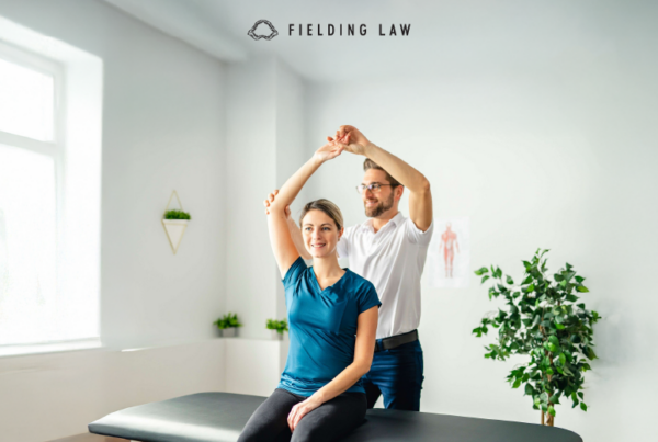 Woman sitting on a table stretching at the chiropractor office. Doctor is standing behind her