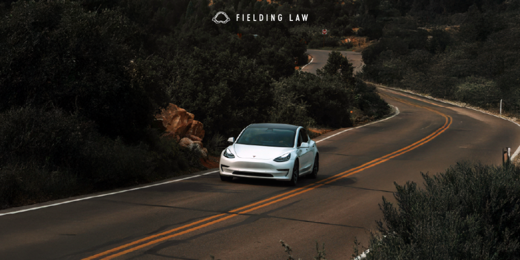 White autonomous car driving on a road with trees around