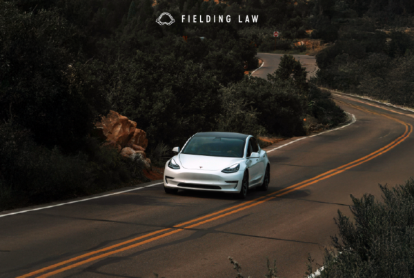 White autonomous car driving on a road with trees around