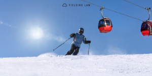 Person skiing down a hill with the sun and ski lift behind them