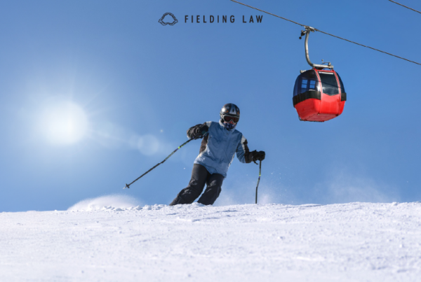 Person skiing down a hill with the sun and ski lift behind them