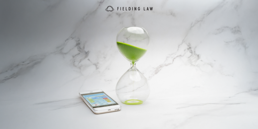 Clear hourglass with green sand running out of time. A phone on the table making a call