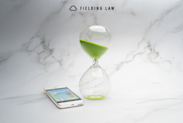 Clear hourglass with green sand running out of time. A phone on the table making a call