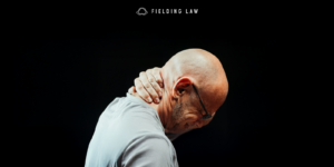 Bald man grabbing the back of his head from whiplash