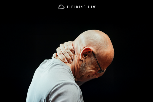 Bald man grabbing the back of his head from whiplash