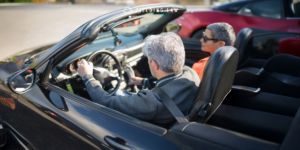 An elderly couple in a convertible car