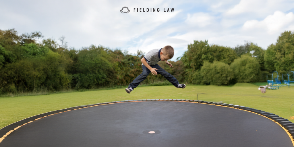 young boy jumping on a trampoline with trees in the background