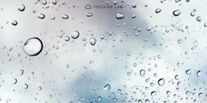 rain drops on glass with the sky blurred in the background