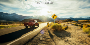 Desert road with a red truck on it with a sharp turn ahead road sign