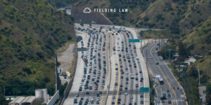 Several vehicles on a Los Angeles freeway with the hills in the background