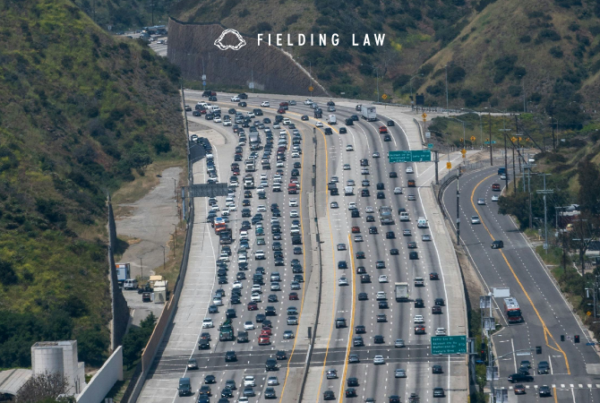 Several vehicles on a Los Angeles freeway with the hills in the background
