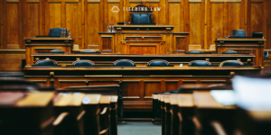 Empty courtroom with multiple black chairs and wooden pews