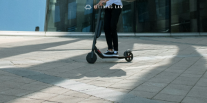 person riding an e-scooter on the sidewalk
