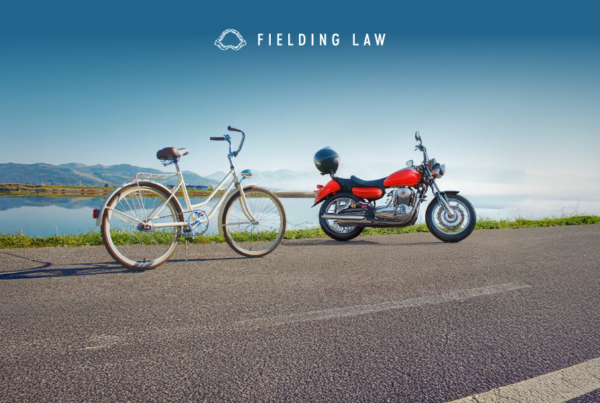 a bicycle and a motorcycle on the side of the road with a lake in the background