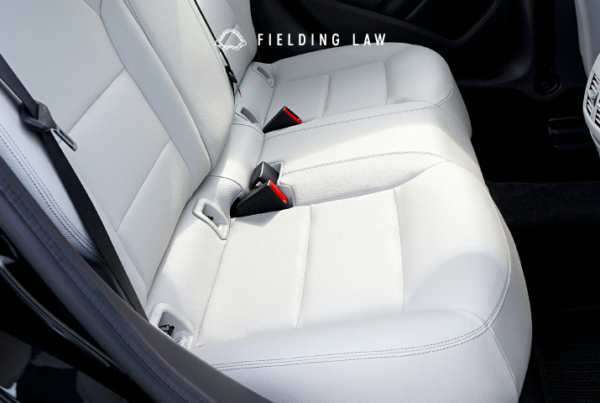 The back of a car with White car seats and black seat belts