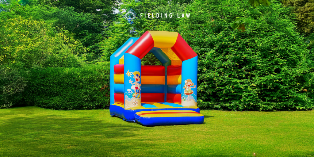 Bouncy House in a grassy yard with trees behind it.