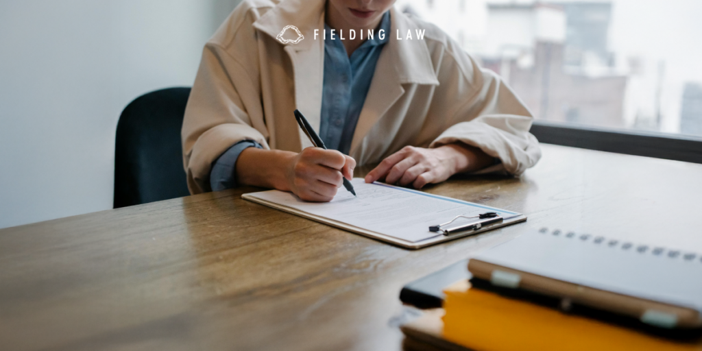 a person sitting at a table writing information from their injury witnesses