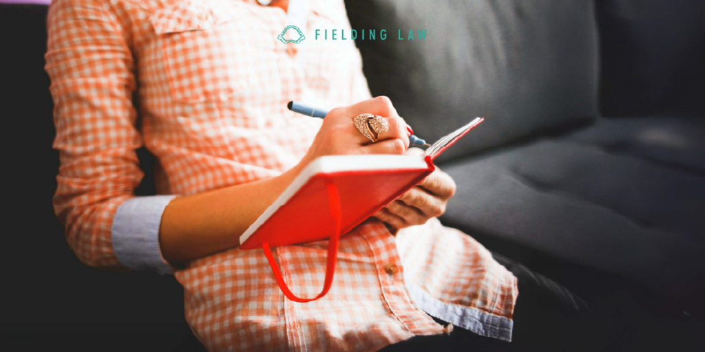 person sitting on a sofa writing in their pain journal