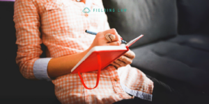 person sitting on a sofa writing in their pain journal