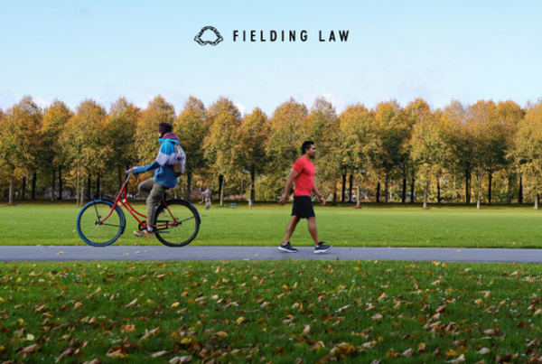 A pedestrian and a person on a bicycle passing each other on a bike path with trees in the background