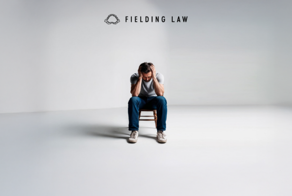 a man with ptsd or fear after his accident sitting on a chair in a white room with this head down and hands on his head
