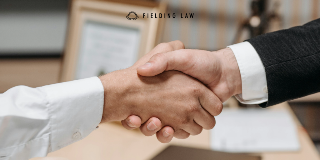two professionals shaking hands in a law office