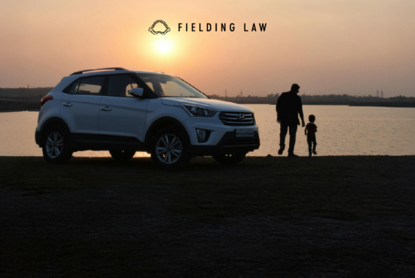 Child with an adult next to a car at sunset