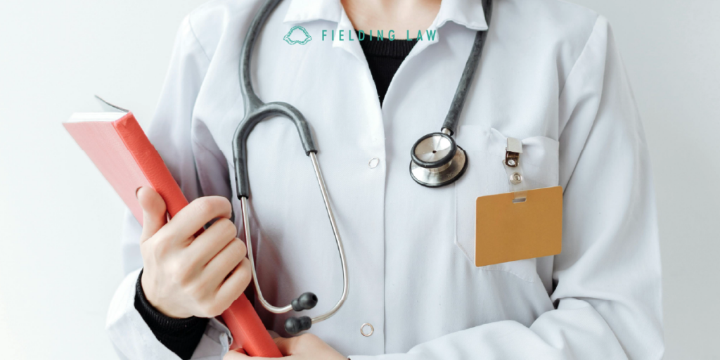 Doctor in white coat with stethoscope holding a red book