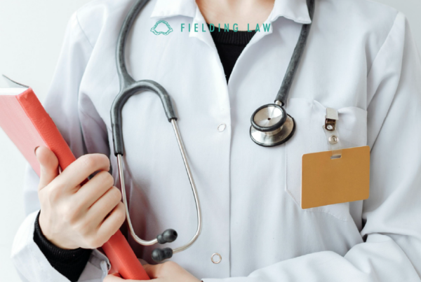 Doctor in white coat with stethoscope holding a red book