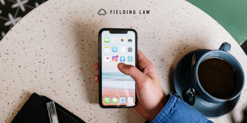 Hand holding a phone at a table with a cup of coffee next to it
