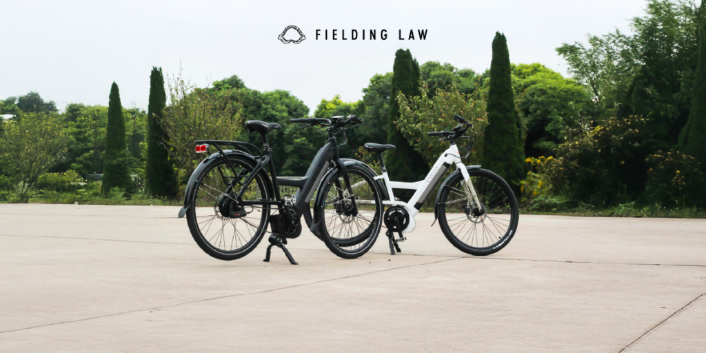 two e-bikes sitting on cement with trees in the background