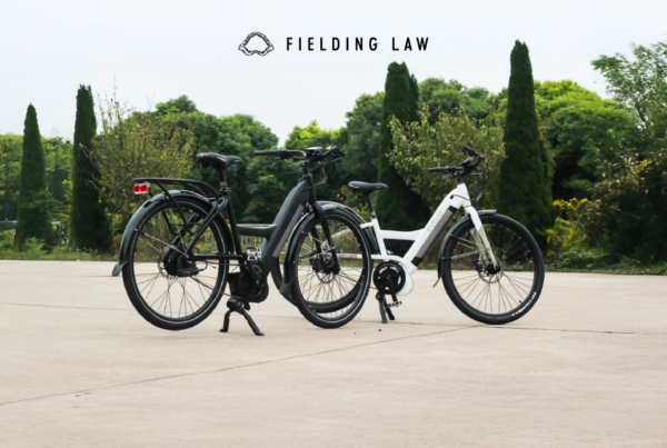 two e-bikes sitting on cement with trees in the background