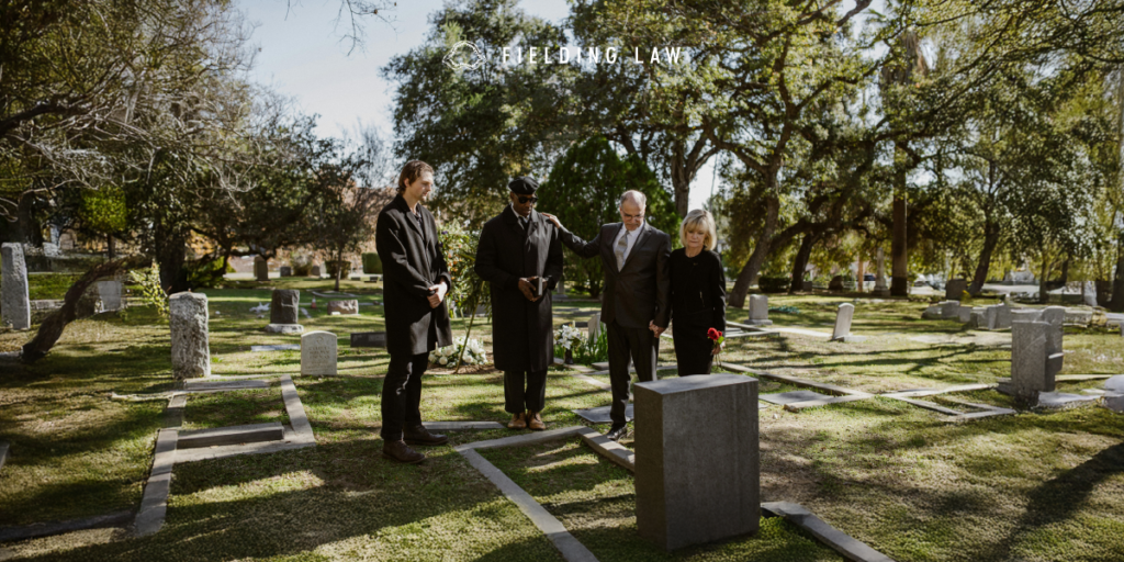 4 people in black clothing at a gravesite